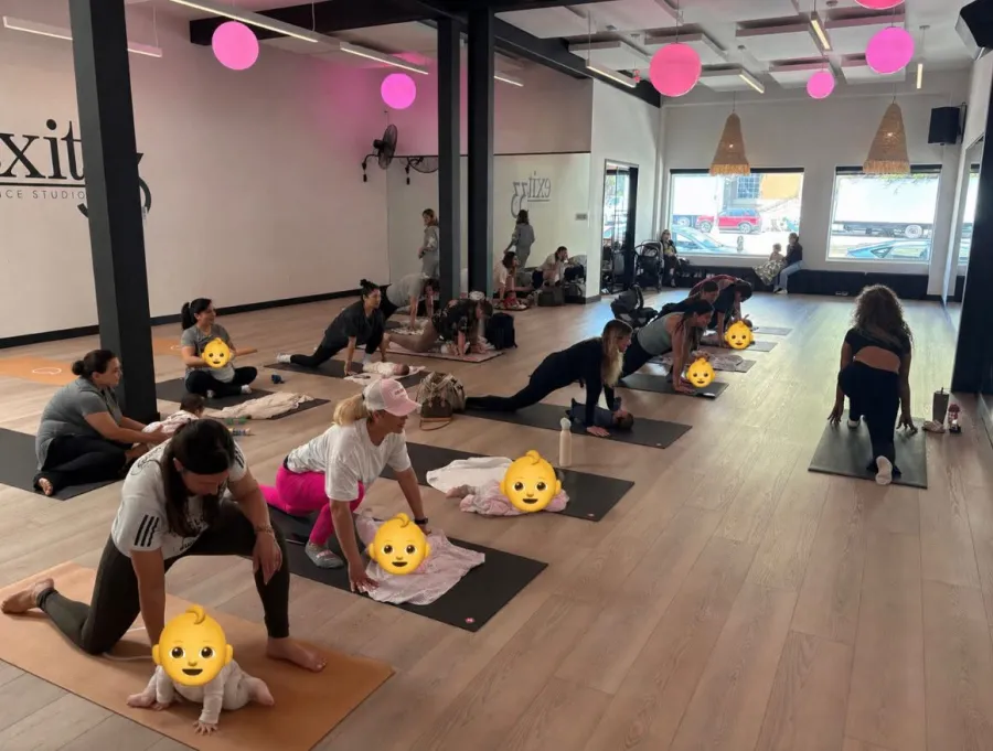 Moms and babies taking part in a group movement class, with the babies' faces covered by emoji for privacy